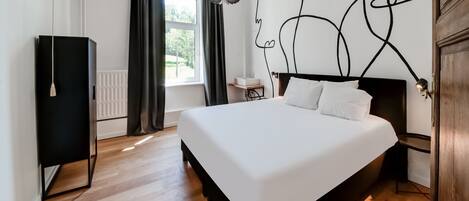 Un dormitorio moderno con una cama grande, suelo de madera, un radiador, un armario y una ventana con cortinas.