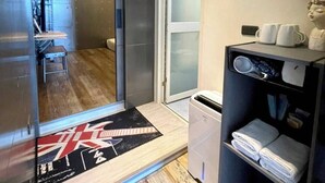 A compact hotel room with a sliding door leading to a balcony, a small kitchenette, and a seating area with a view. - Enjoy kenting (Hengchun)