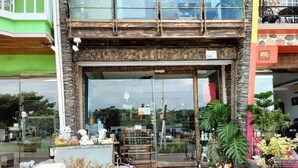 A storefront with a glass door, potted plants, and a signboard in front. - Enjoy kenting (Hengchun)