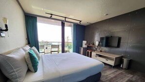 A modern hotel room with a large bed, a desk, a TV, and a balcony with a view. - Enjoy kenting (Hengchun)
