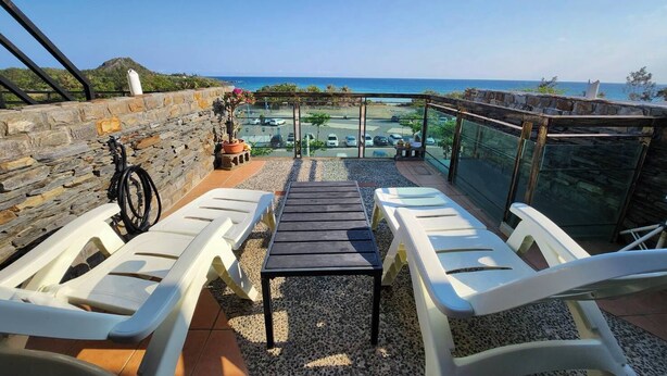 A balcony with white lounge chairs, a small table, and a view of the sea and parking area. - Enjoy kenting (Hengchun)