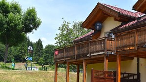 A wooden building with a balcony, a sign indicating a ski resort, and a grill area. - Chalet in Kotschach by Ski Slopes (Kotschach-Mauthen)