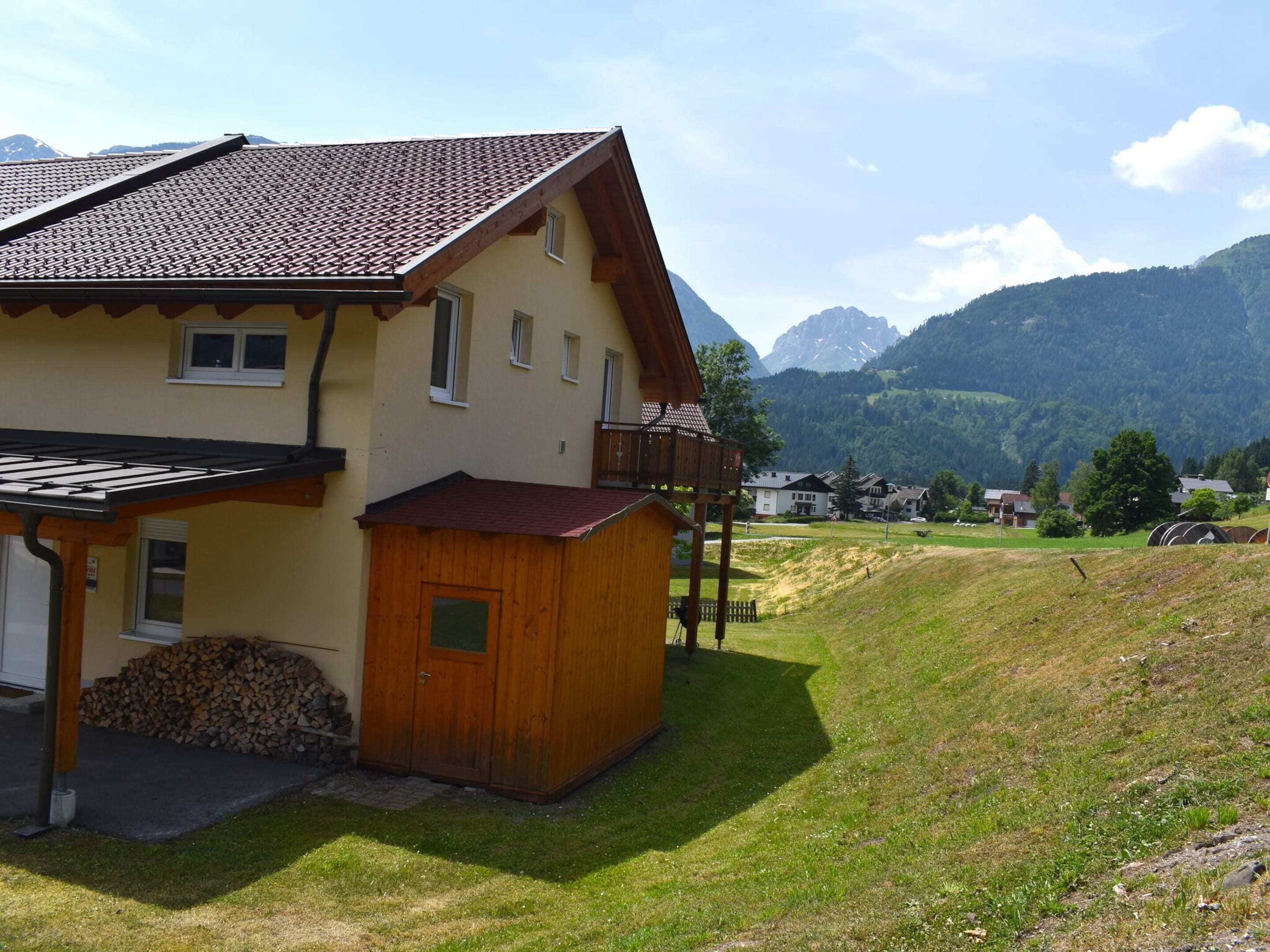 Una casa a due piani con tetto spiovente, un capanno di legno e un cortile erboso.