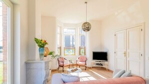 Un salon avec un canapé, deux fauteuils, un téléviseur et une cheminée.