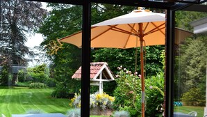 Un espace patio avec une table et des chaises, un chien et un grand parasol.