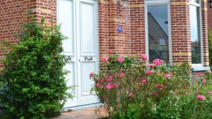 Un bâtiment en briques avec une porte blanche et une plaque d’immatriculation bleue.