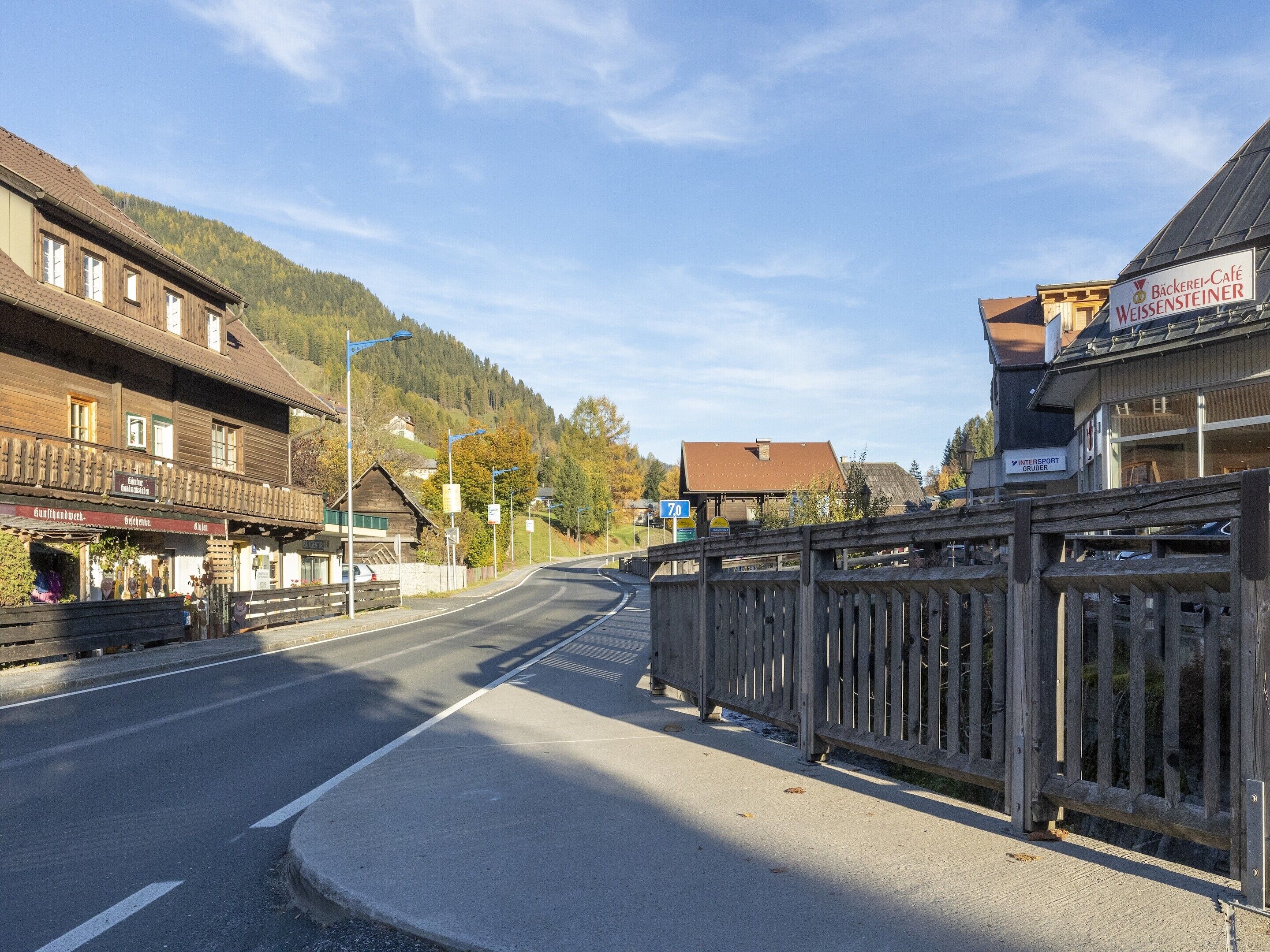 Una calle con edificios, una valla de madera y un letrero de café.