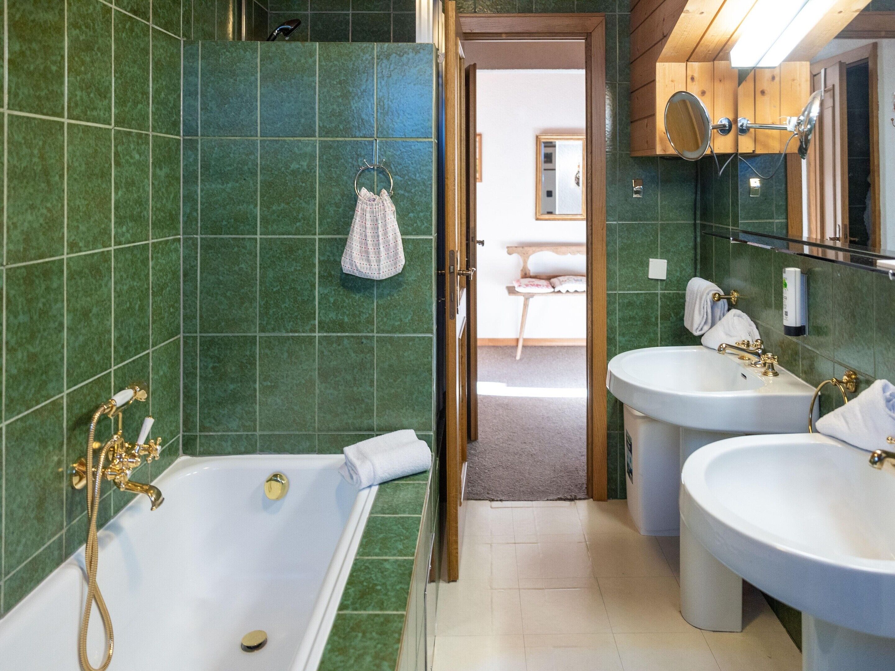 Een badkamer met een bad, twee wasbakken en een spiegel.