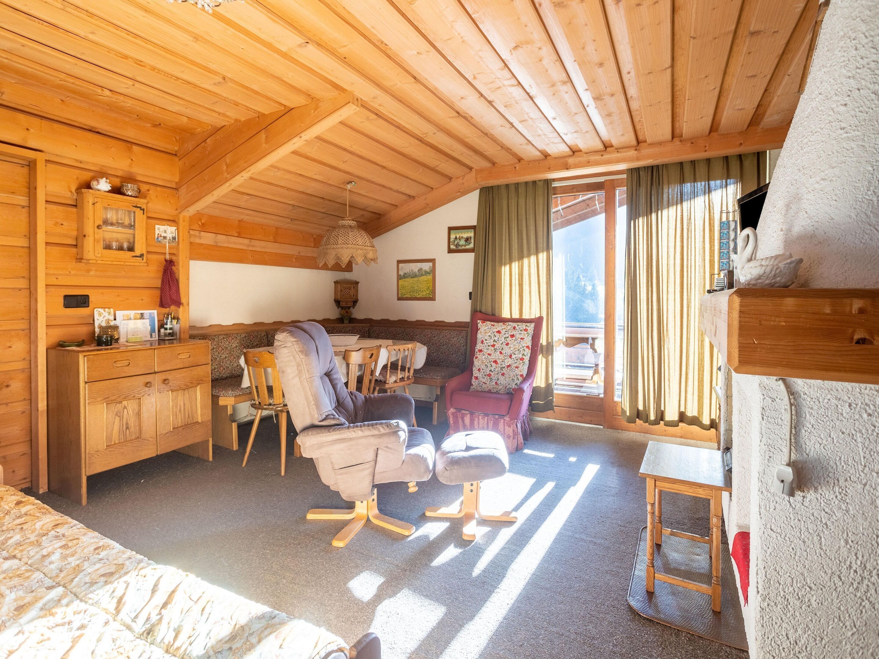 A cozy wooden cabin with a dining area, a sofa, and a chair.