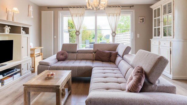 Una sala de estar con un sofá modular, una mesa de centro de madera, un televisor y un mueble.