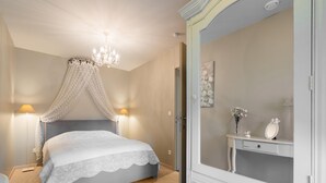 Un dormitorio con cama, candelabro, mesita de noche y cómoda con espejo.