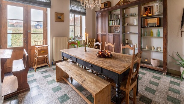 A rustic dining room with a wooden table, benches, and a chandelier.