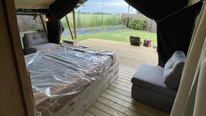 A tented accommodation with a bed, two sofas, and a view of a grassy field. - Holiday Home in Vlijtingen With Sauna (Riemst)
