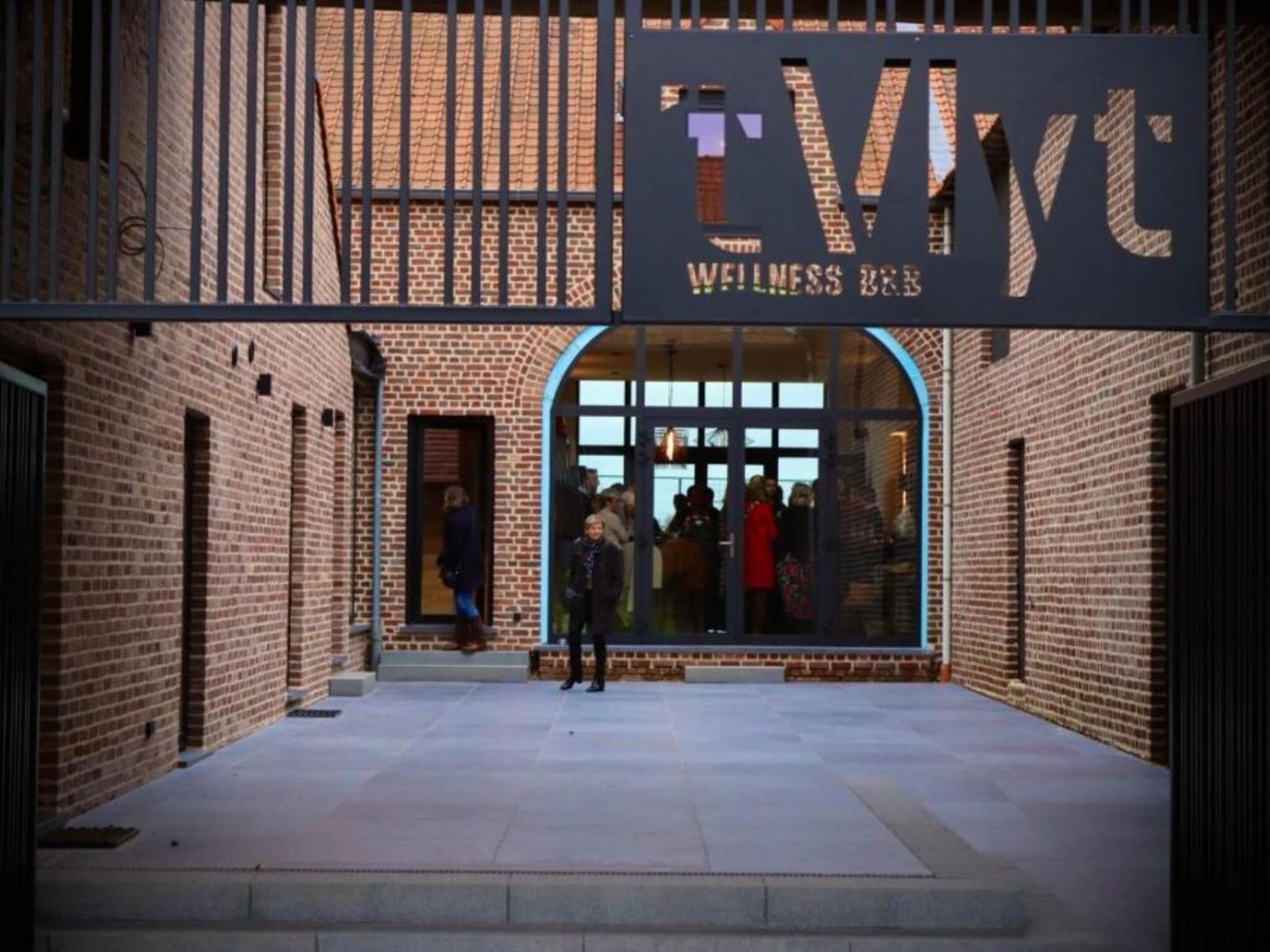 En murbygning med en stor buet indgang og et skilt, der står 'TWYC WELLNESS B&B'.