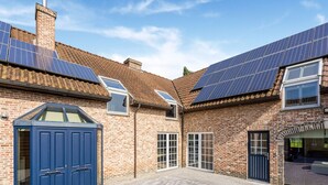 A courtyard with a brick building, solar panels, and a blue door. - Alken Farm Stay With Terrace (Alken)