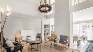 A spacious living room with a piano, wicker chairs, a round ottoman, and a hanging light fixture. - Alken Farm Stay With Terrace (Alken)