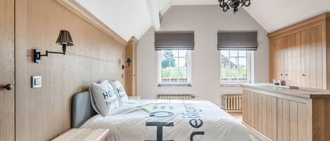 A bedroom with a bed, bedside table, lamp, and a view of the outside.