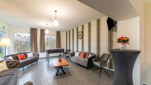 A modern living room with sofas, a foosball table, and a flat-screen TV. - Holiday Home in Waimes With Garden (Waimes)
