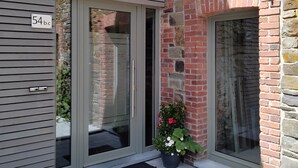 A building entrance with a glass door, a stone wall, and a potted plant. - Holiday Home in Waimes With Garden (Waimes)