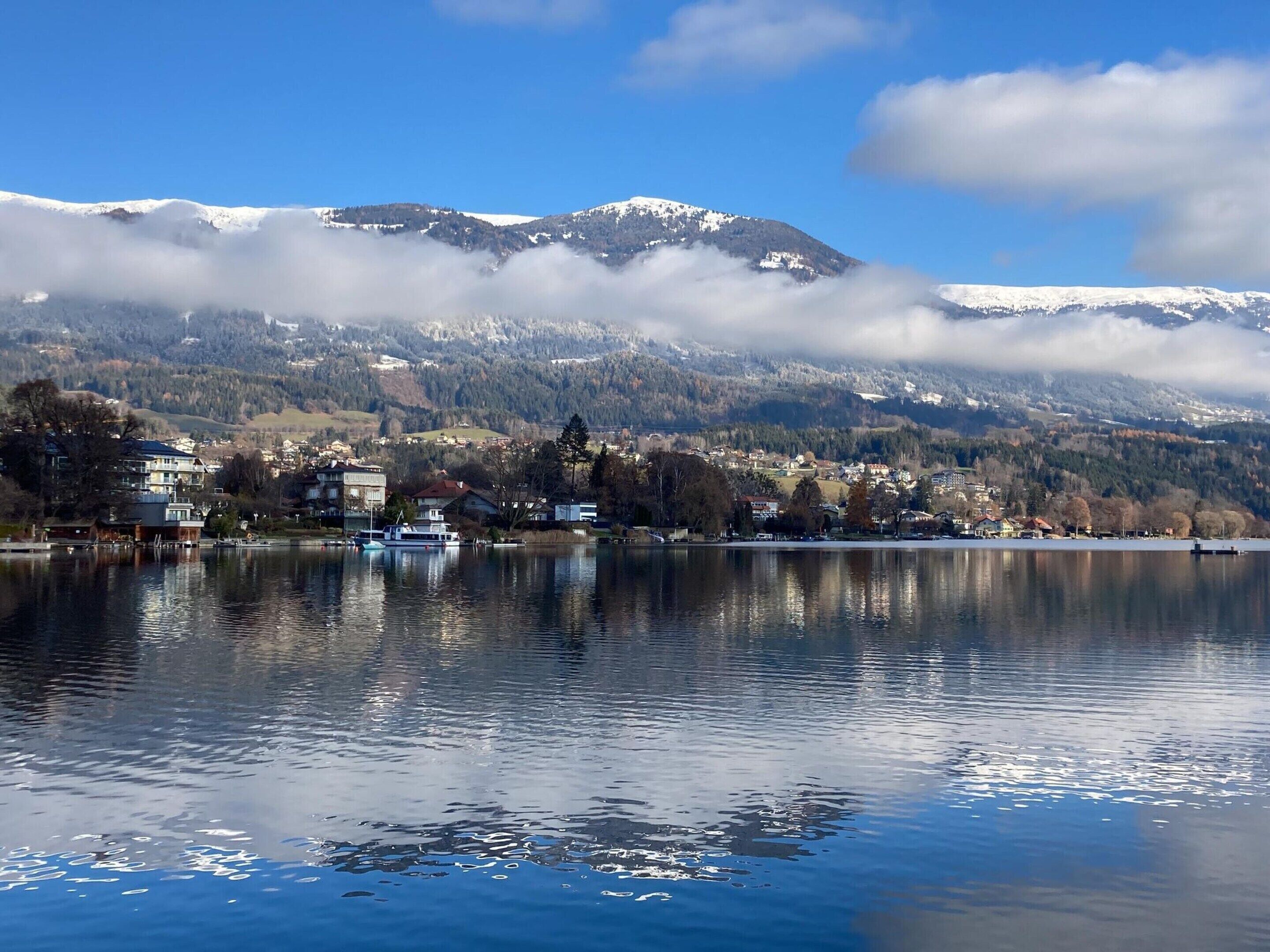 Un lago con un pueblo y montañas al fondo.