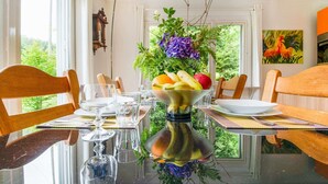 A dining table with chairs, a fruit bowl, and a vase with flowers. - Cozy Hideaway in Ferrieres (Ferrieres)