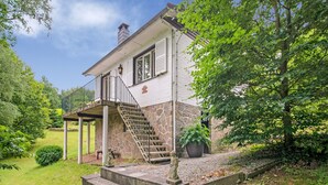 A two-story house with a stone foundation, a covered porch, and a staircase leading to the second floor. - Cozy Hideaway in Ferrieres (Ferrieres)