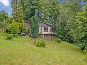 A house with a stone foundation, a balcony, and a garden with various plants and a lawn. - Cozy Hideaway in Ferrieres (Ferrieres)