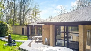 Ein modernes Haus mit Terrasse, Essbereich und großem Fenster mit Blick auf den Garten.