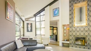 Ein geräumiges Wohnzimmer mit Ledersofa, runder Couchtisch und Kamin.