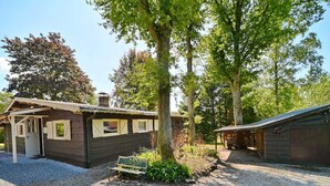 A rustic cabin with a gravel driveway, a wooden bench, and a small garden area. - Chalet in Biron With Large Garden Near Durbuy (Erezee)