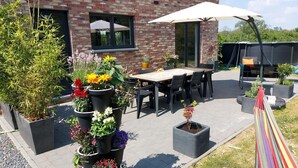 Un espace patio avec un bâtiment en briques, des sièges extérieurs et des plantes en pot.