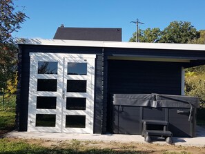 Une maison moderne avec un garage, un espace extérieur aménagé et abrité, et un ciel dégagé.
