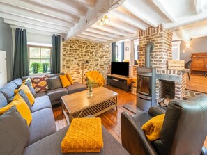 A living room with a stone wall, a fireplace, a sofa, a television, and a coffee table. - Theux Farmhouse With Garden (Theux)