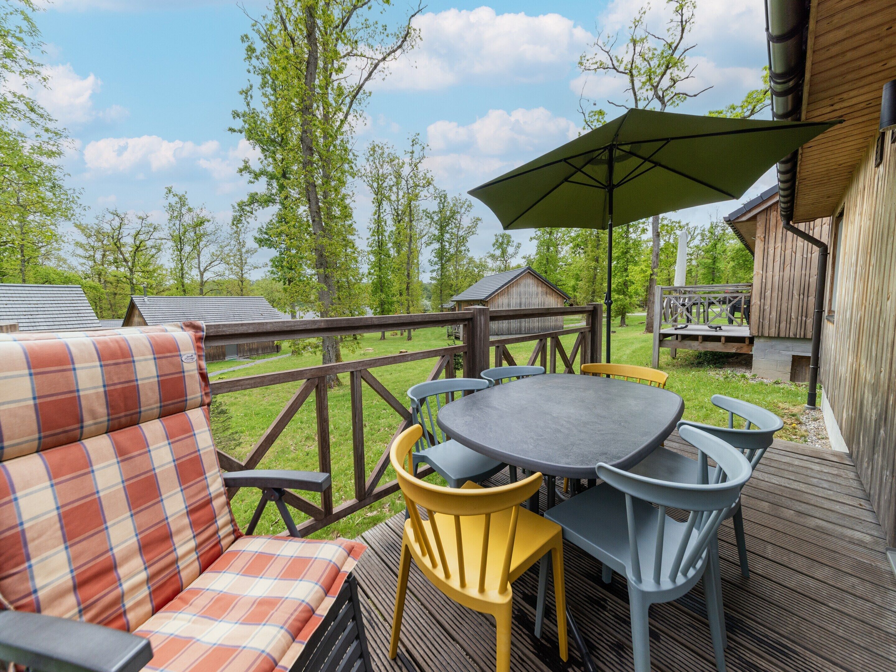 A deck with a table and chairs, a sofa, and a wooden fence.