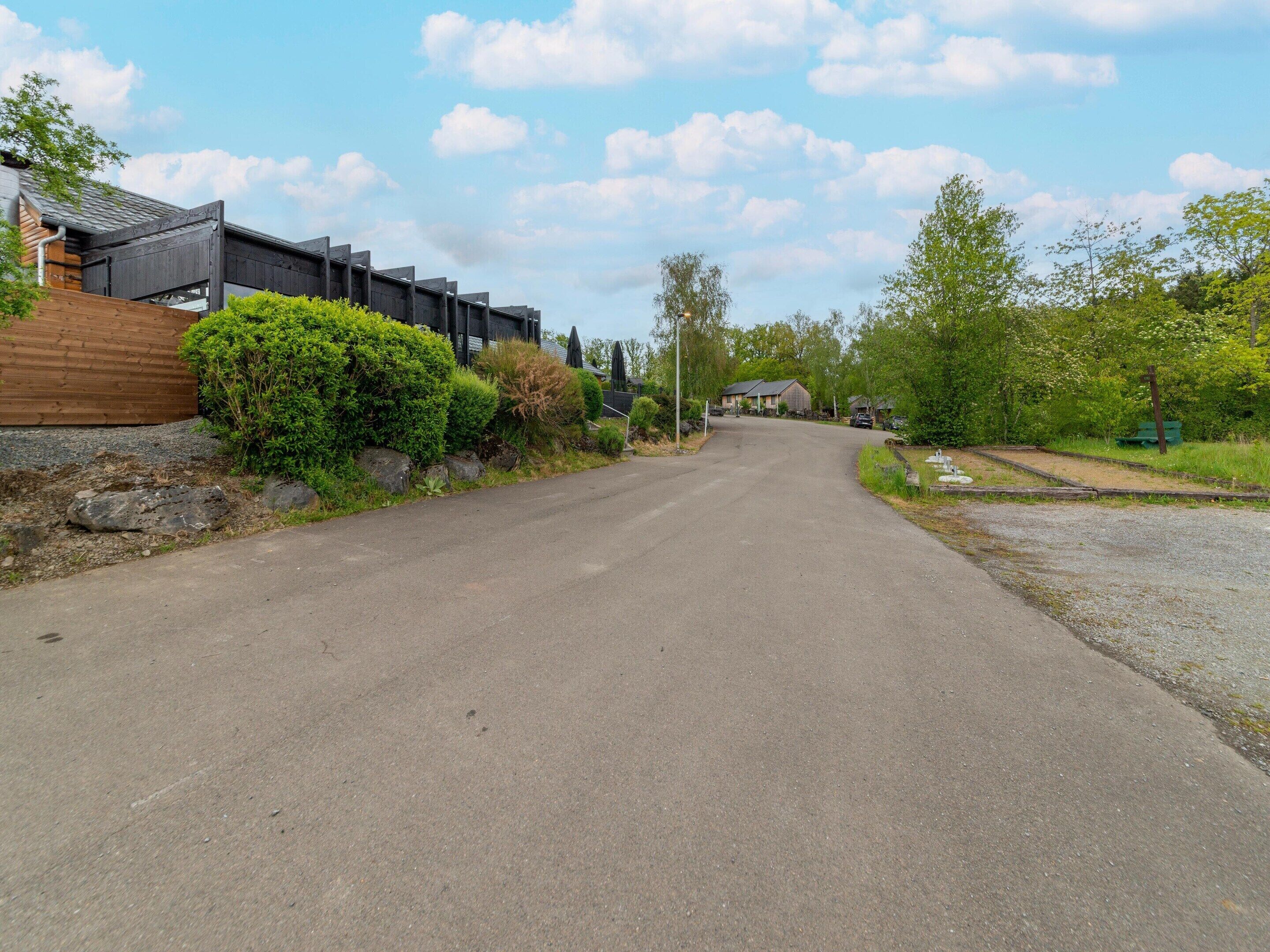 A residential street with houses, a wooden fence, and greenery.