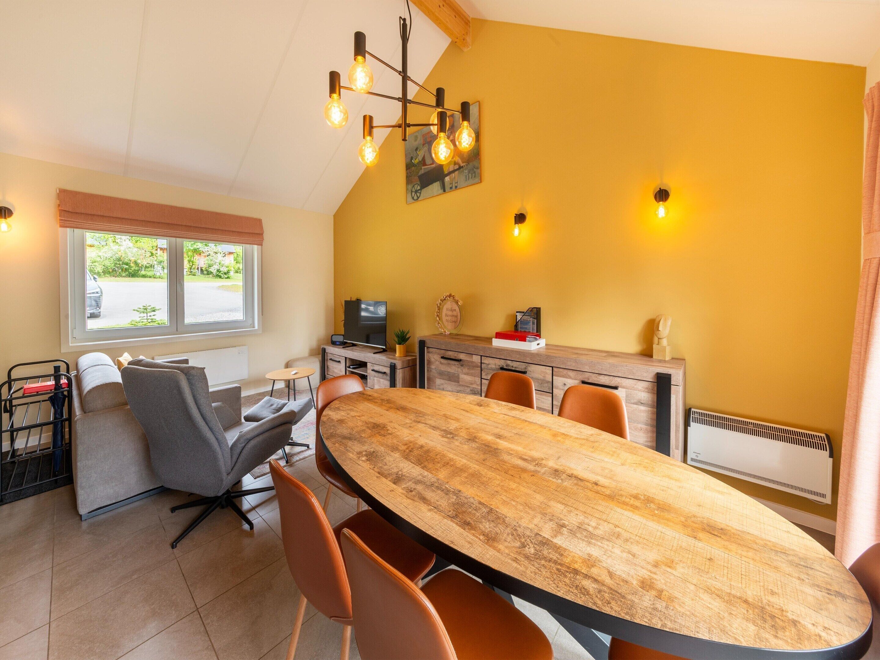 A dining area with a wooden table and chairs, a television, and a radiator.