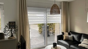 Una sala de estar moderna con un sofá de cuero negro, una mesa de centro redonda y una lámpara colgante.