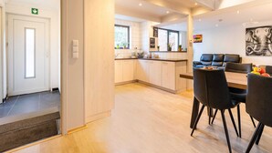 A modern kitchen with a central island, a dining area with black chairs, and a large window providing natural light. - Herselt Garden Shed Retreat (Herselt)