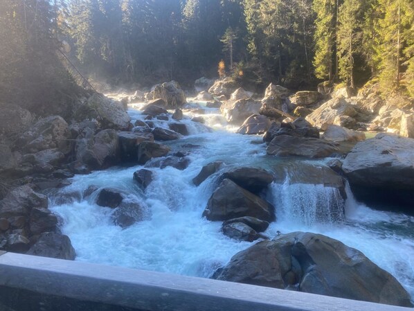 A river flowing through a rocky landscape with a wooden railing in the foreground. - Holiday Home in Carinthia Near ski Area (Gitschtal)