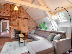 A loft-style room with exposed brick walls, a wooden bench, a sofa, and a large window.