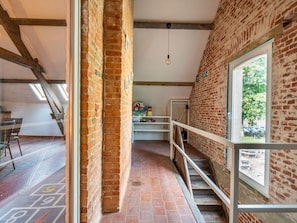 A room with a brick wall, a window, a staircase, and a shelf with toys.