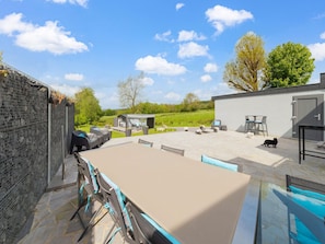 An outdoor patio with a table and chairs, a barbecue area, and a small covered seating area.
