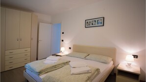 Une chambre à coucher bien rangée, avec un lit, des tables de chevet, une armoire et un tableau accroché au mur.