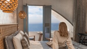 A bedroom with a bed, pillows, a view of the sea, and a balcony. - Almyra Oia Suites Adults Only  (Santorini)