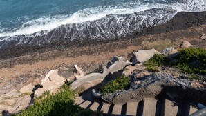A rocky shoreline with waves crashing onto the beach. - Almyra Oia Suites Adults Only  (Santorini)