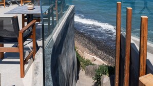 A seaside restaurant with outdoor seating overlooking the ocean. - Almyra Oia Suites Adults Only  (Santorini)
