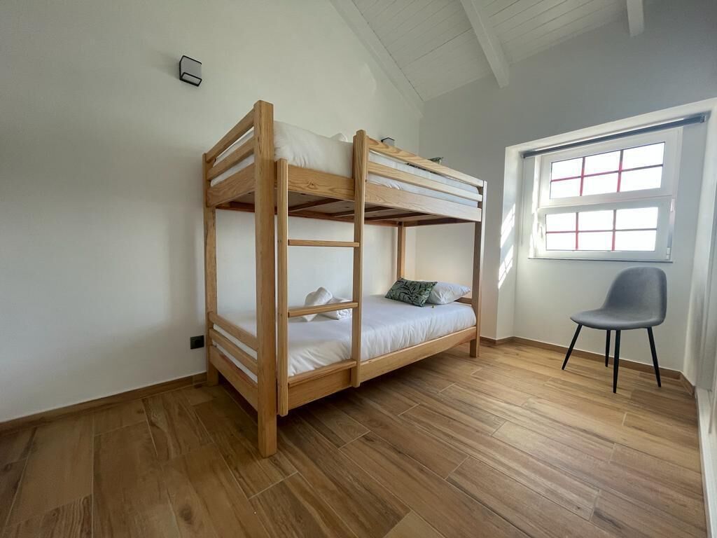 Quarto com beliche, janela e uma cadeira.