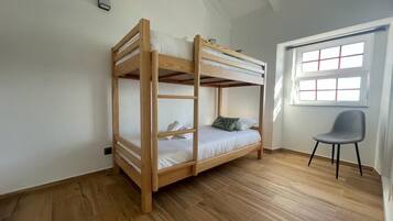 Quarto com beliche, janela e uma cadeira.