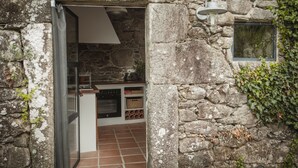 A rustic stone kitchen with a built-in oven, a hanging light fixture, and a window with ivy. - One of two private and intimate casitas. Surrounded by nature. (Moraña)