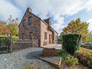 Une maison en briques avec un toit en pente, une porte en bois et une allée gravillonnée.